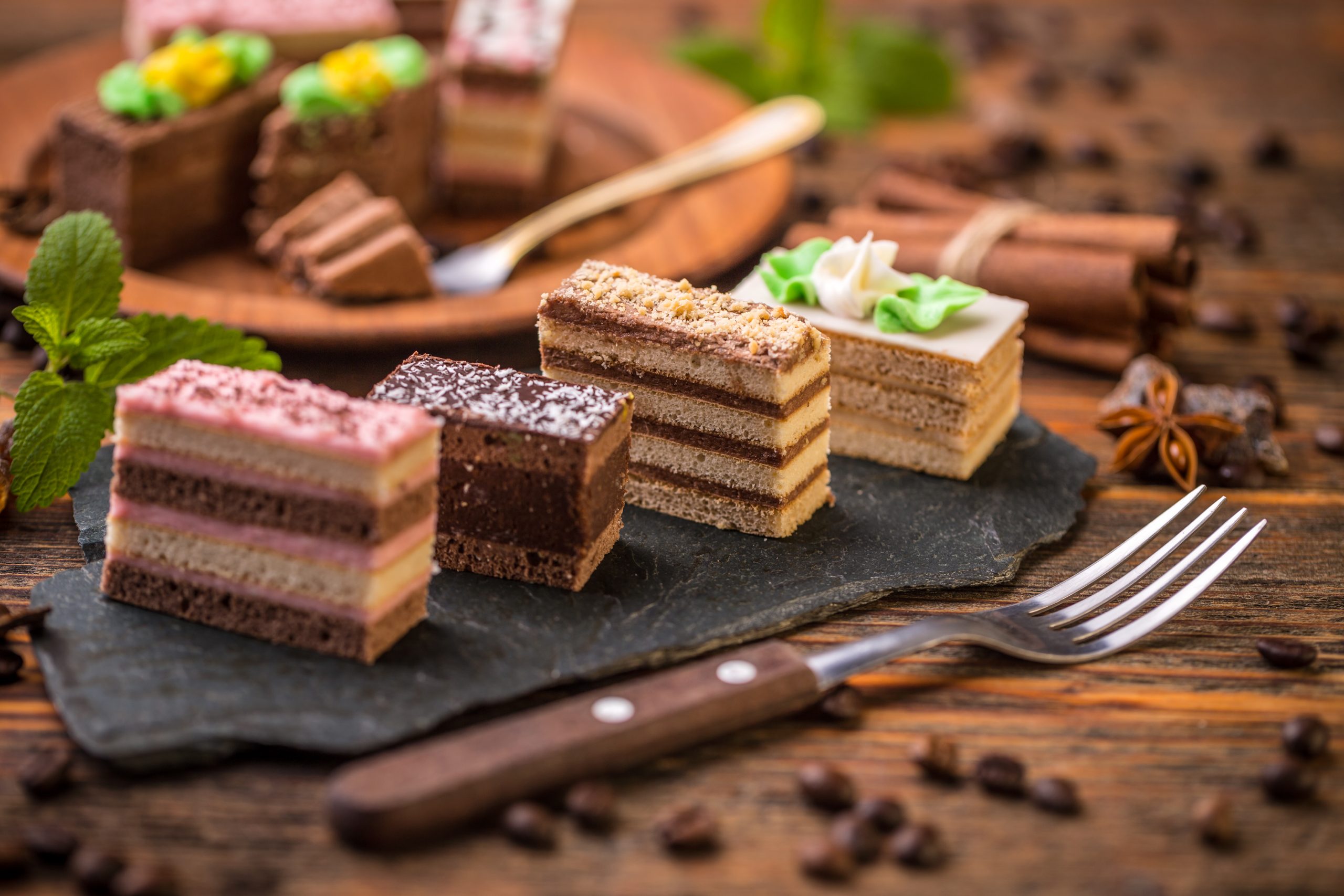 Small square cakes with different cream on black slate